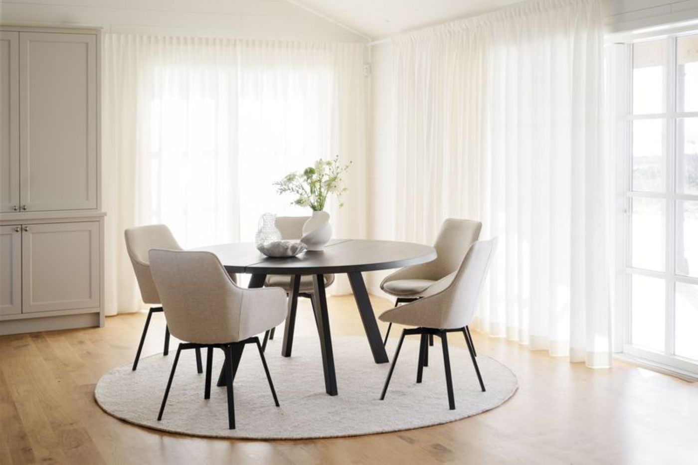 Runder Teppich und ein runder Esstisch mit 4 Stuhlen aus dunklem Holz